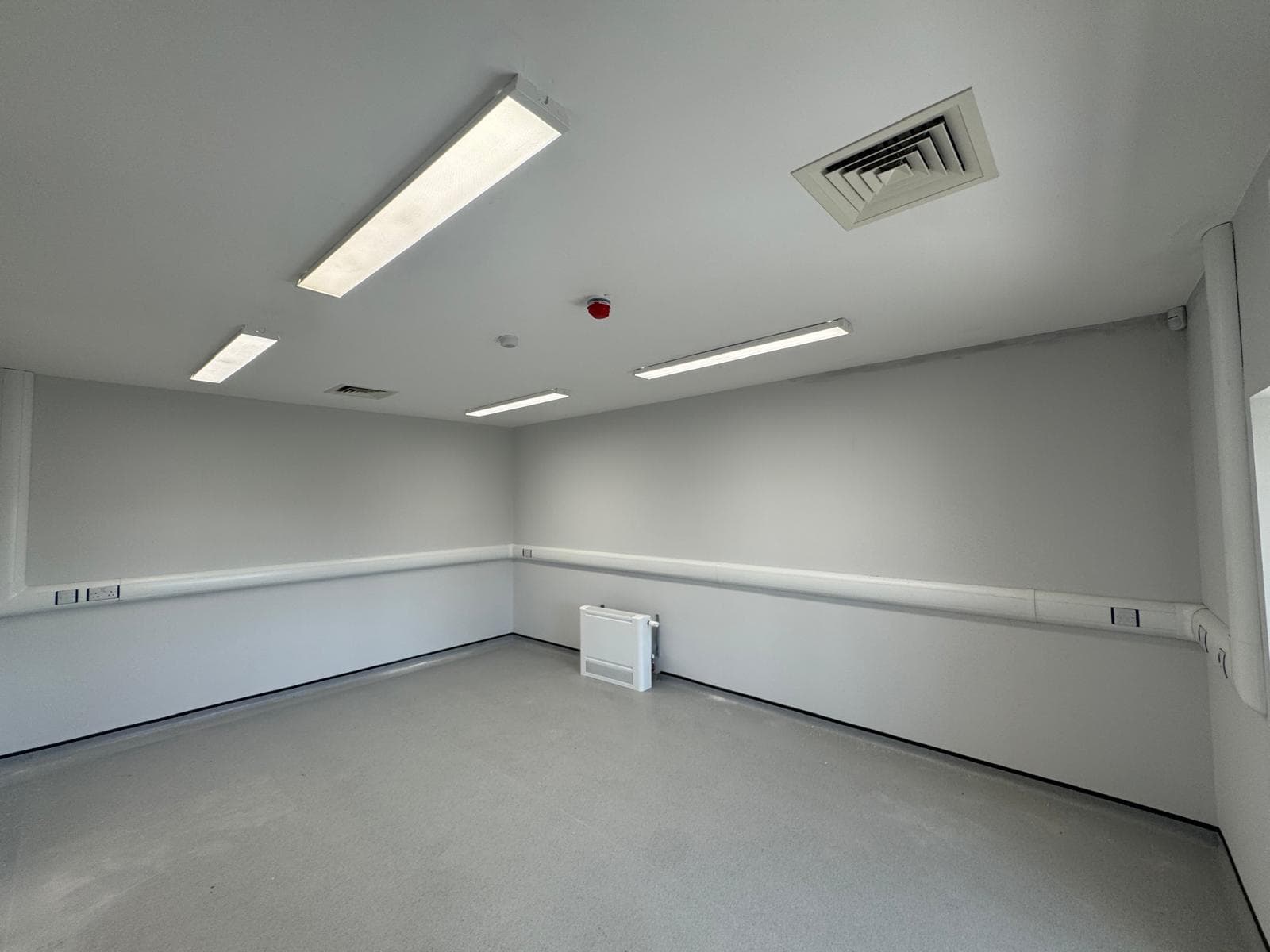 Surface mounted LED battens lit on the ceiling of an empty commercial room