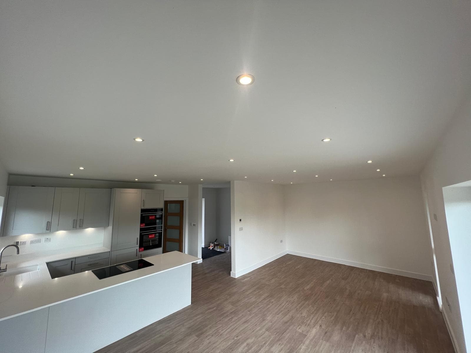 A finished open plan kitchen and living room in a new build, with the lighting installed and lit