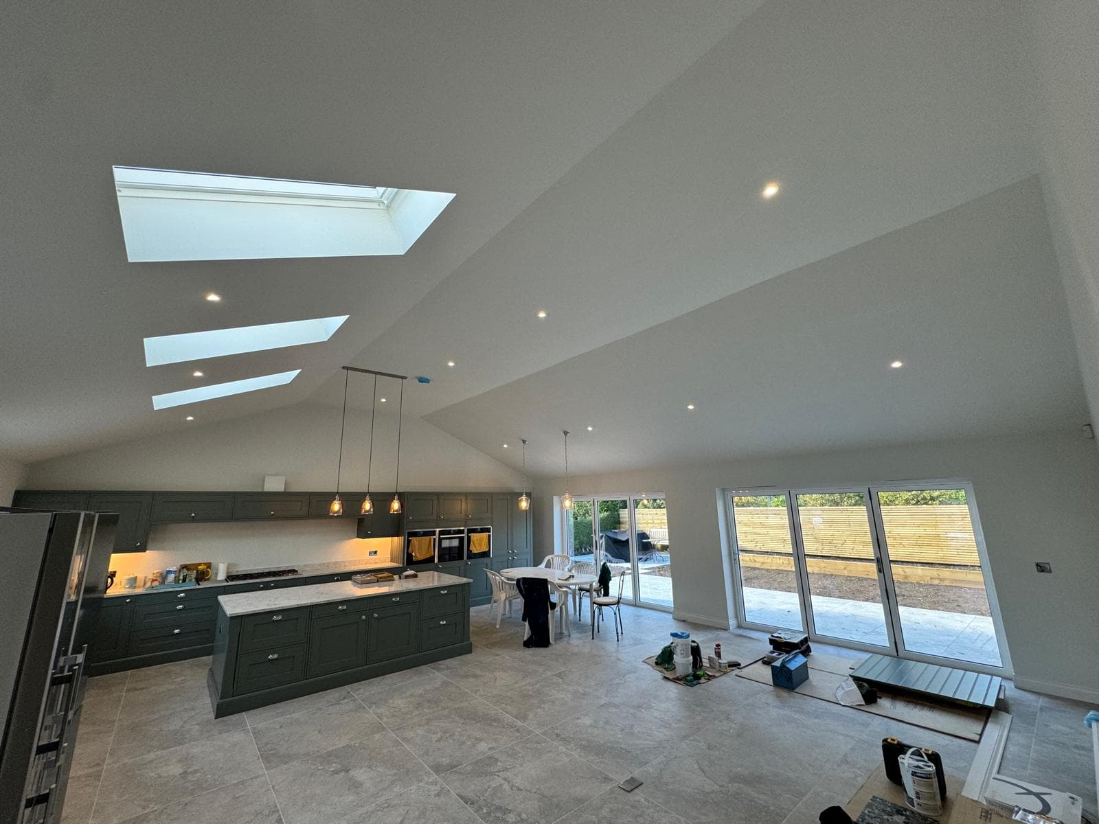 A finished new build kitchen and dining room with pendants and recessed lighting installed
