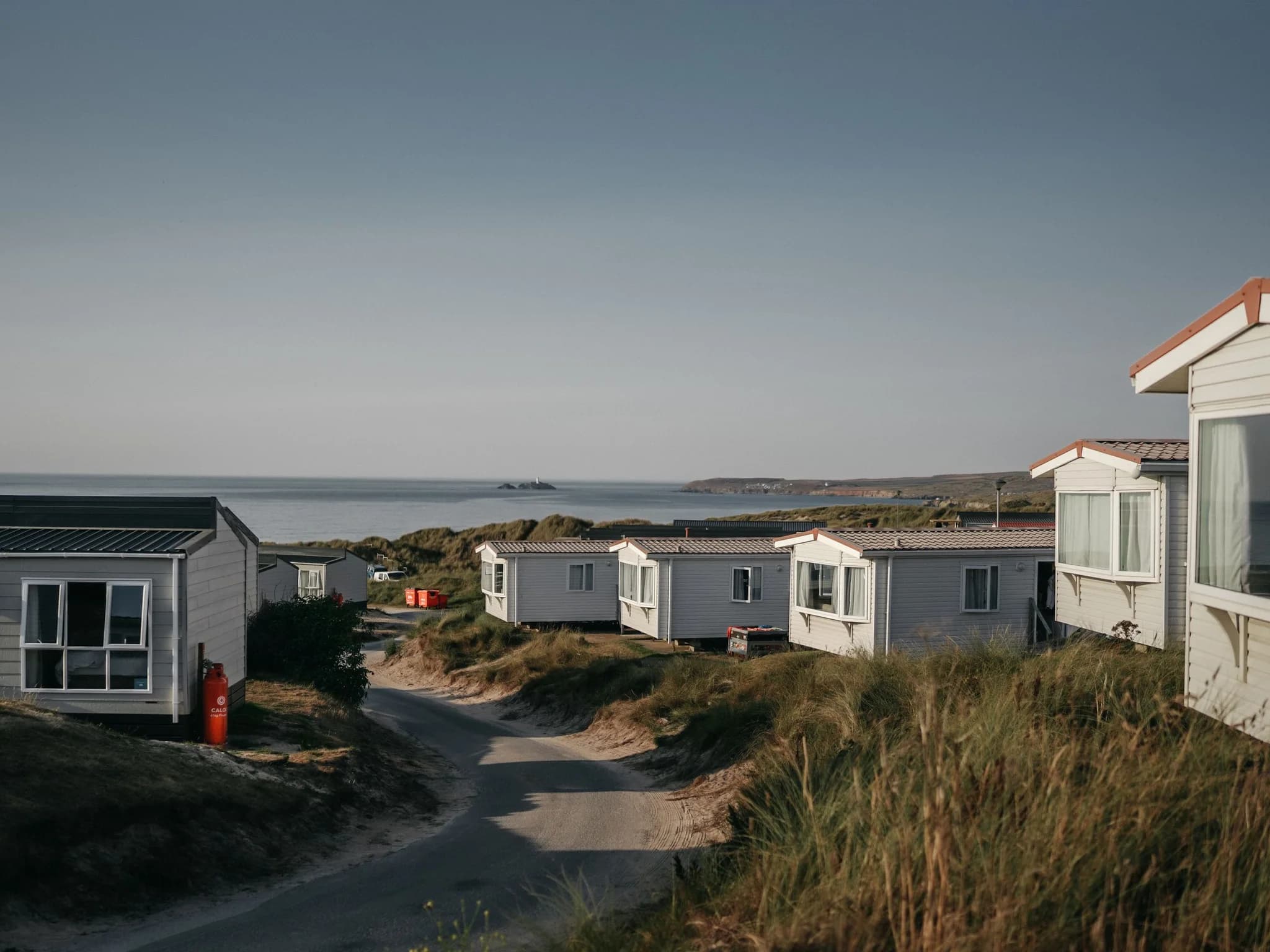 Static caravans on a grassy coastal holiday park with the sea beyond